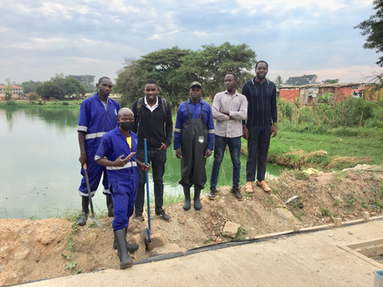 A group photo of sanitation workers dressed in overalls and research assistants at a lagoon in one of the study cities